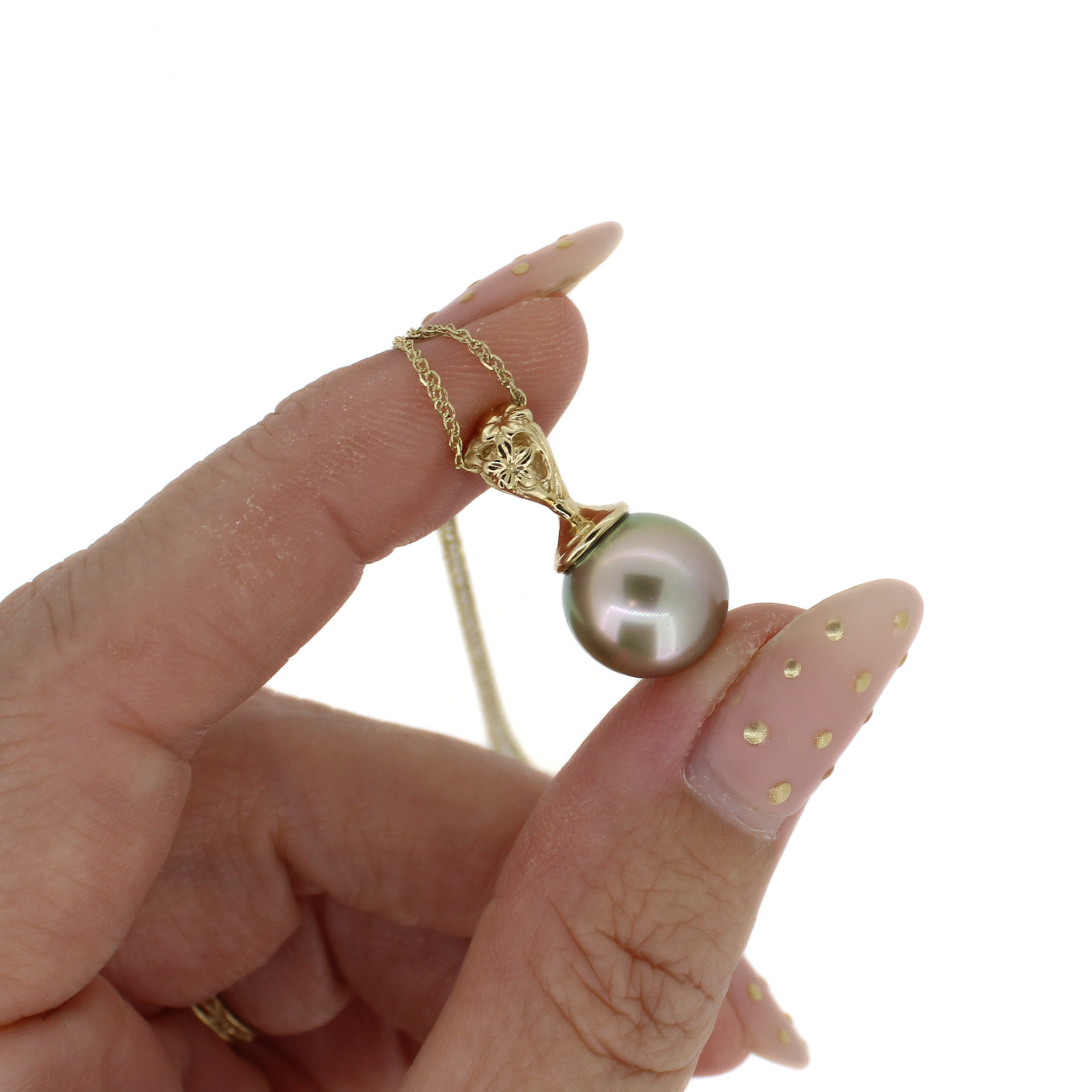 A close-up of a hand holding a gold necklace with a single round pearl pendant against a plain white background.