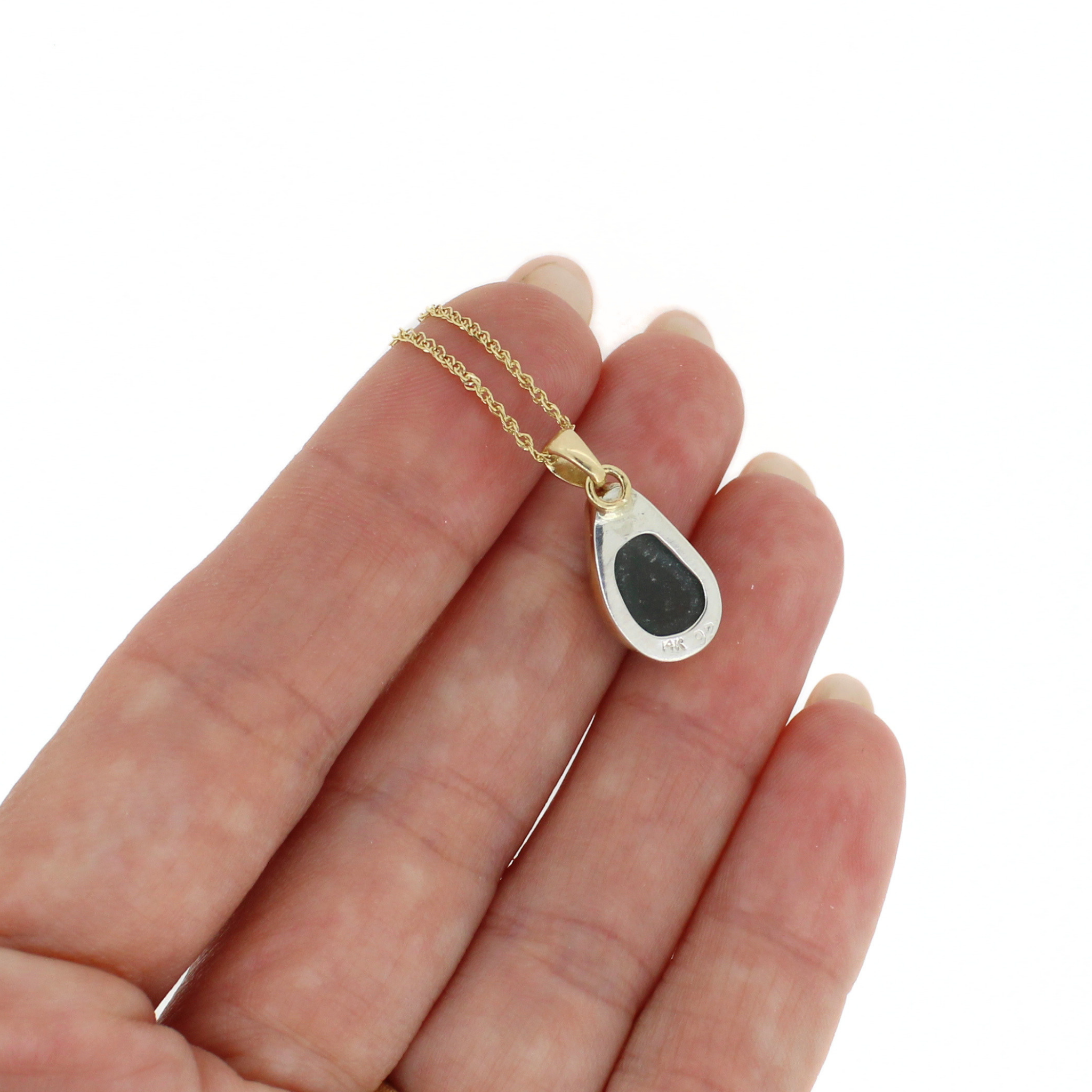 Gold chain necklace with teardrop dark sea glass pendant, close-up