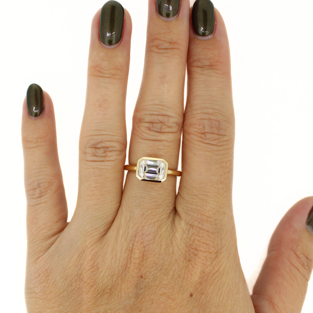 Brianne & Co. emerald cut moissanite ring on hand model