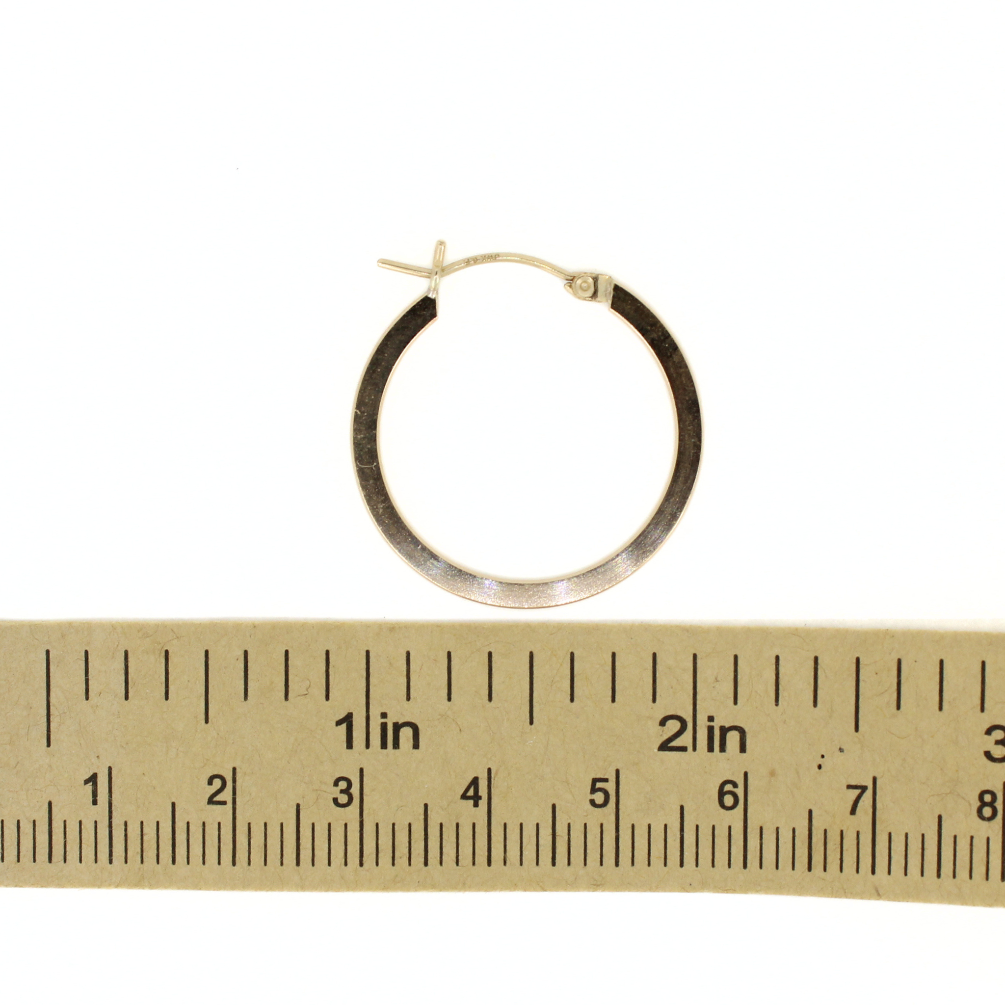 Gold-tone flat hoop earring, 27mm, next to ruler for size reference