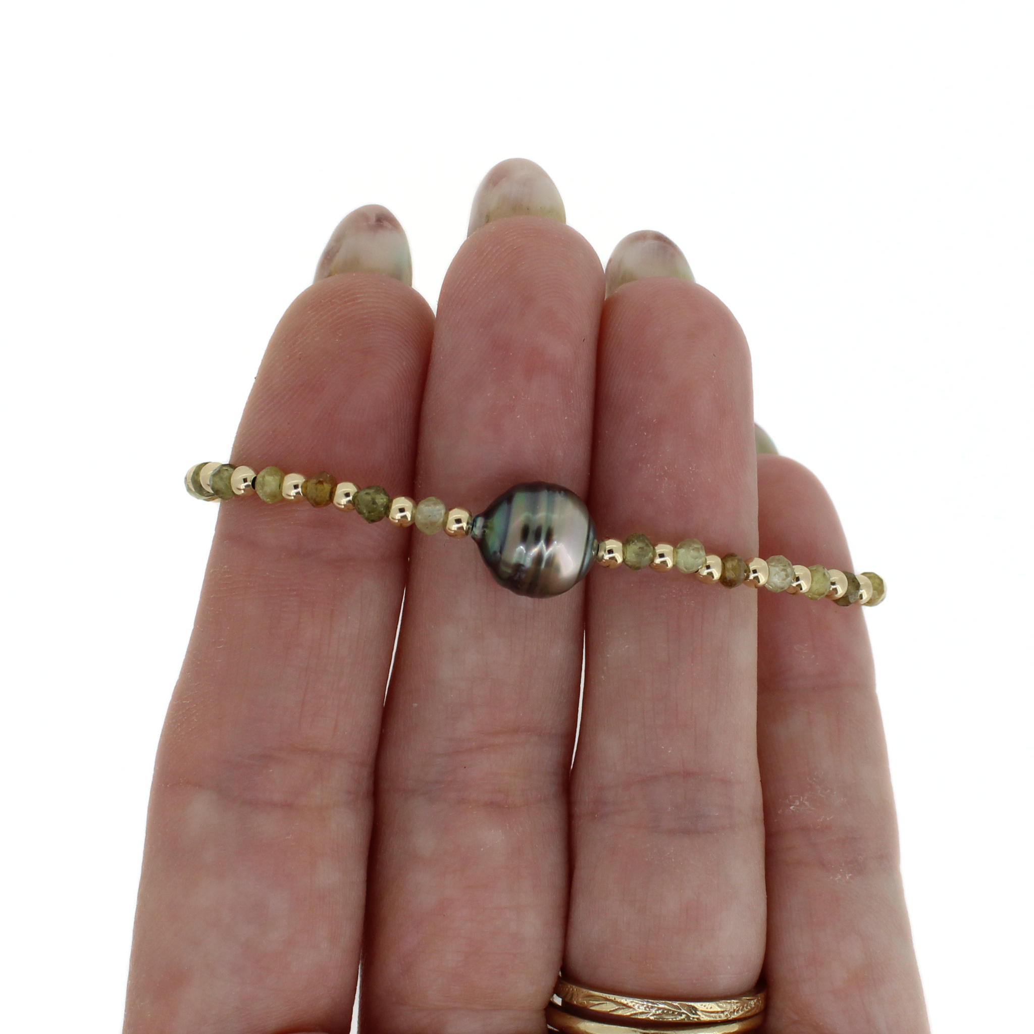 Beaded bracelet with round dark Tahitian-style pearl center, on palm