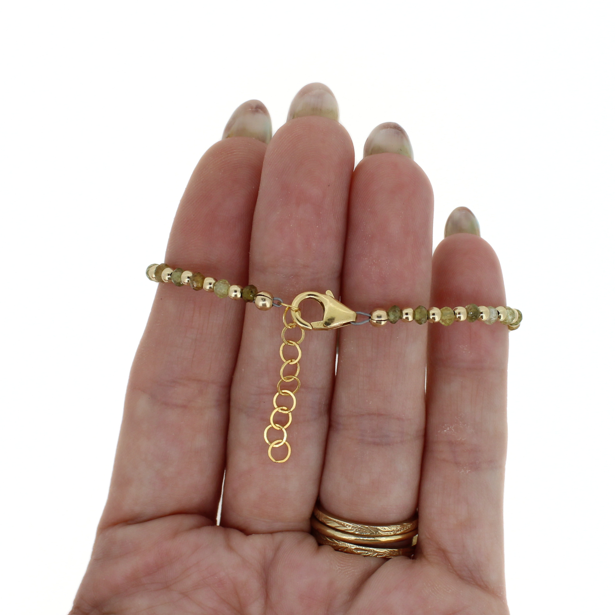 Gold beaded bracelet with round dark Tahitian-style pearl and gold toggle clasp, on hand