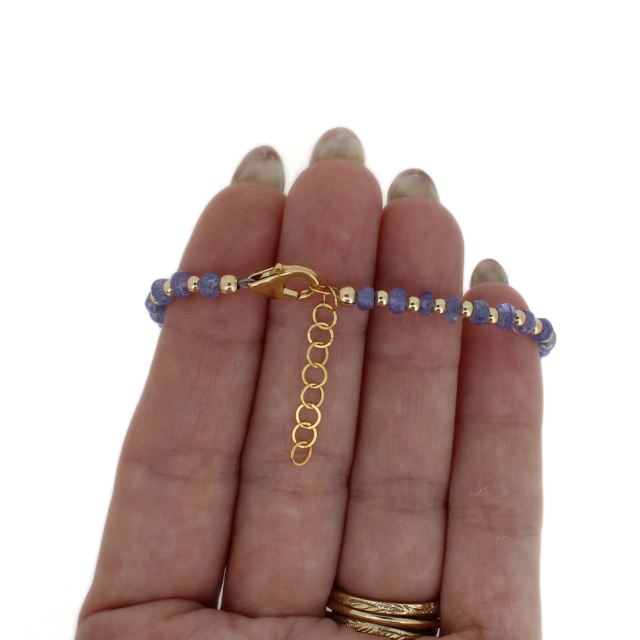 Handheld bracelet detail: gold toggle clasp, dark blue beads, large gray baroque pearl.