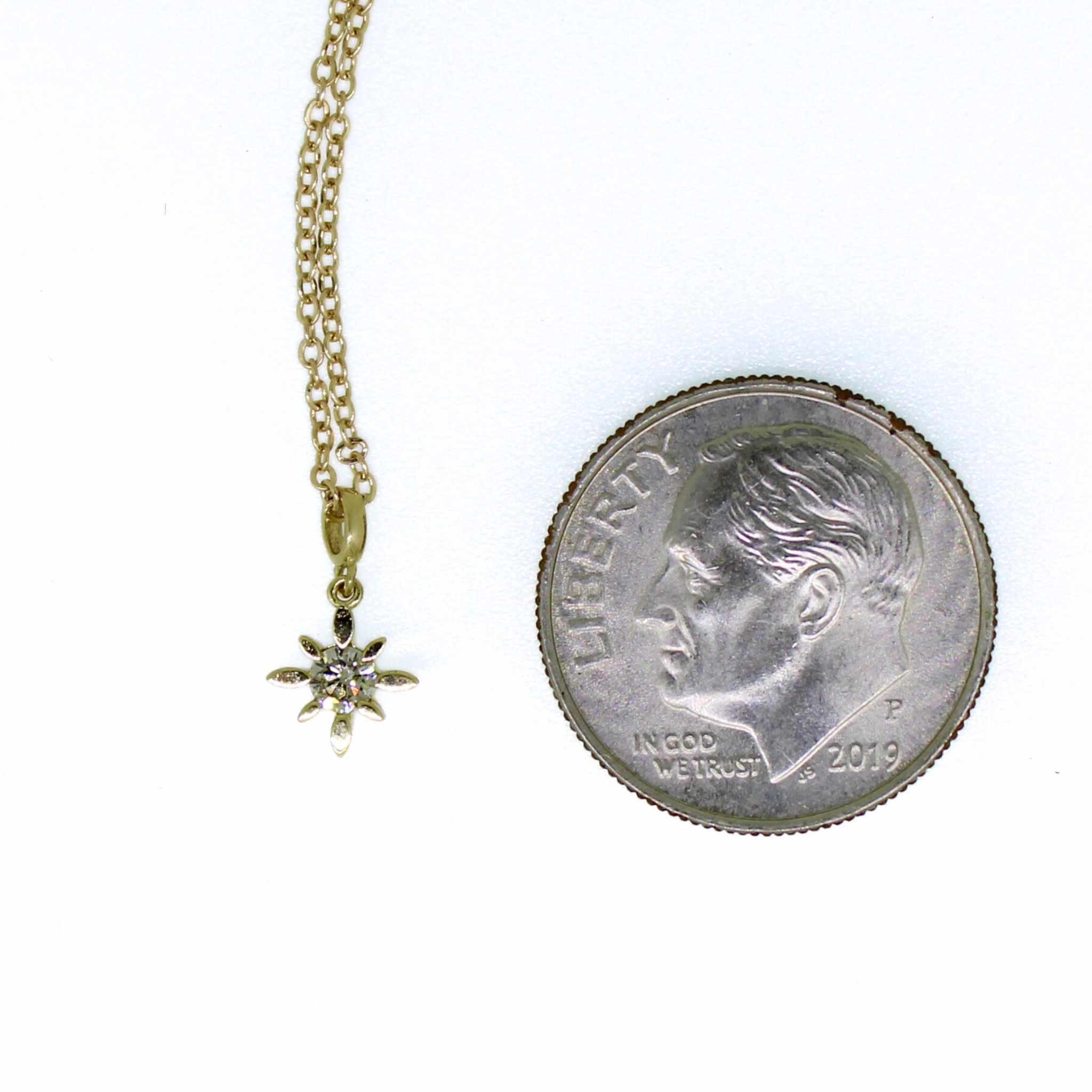 Brianne & Co. 14k gold diamond star necklace next to a US dime for size reference