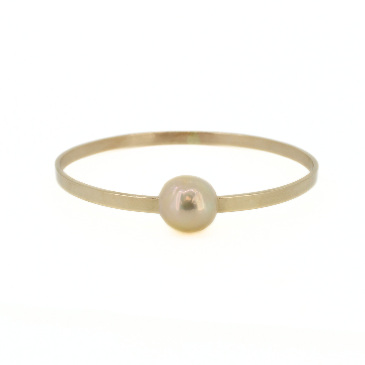 A minimalist gold bangle bracelet featuring a single, smooth, lustrous pearl set in the center, photographed against a seamless white background.