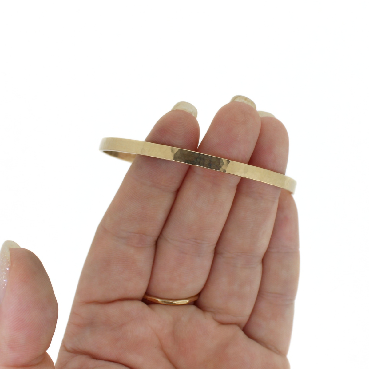 Gold hammered bangle bracelet shown on a persons fingers for size reference