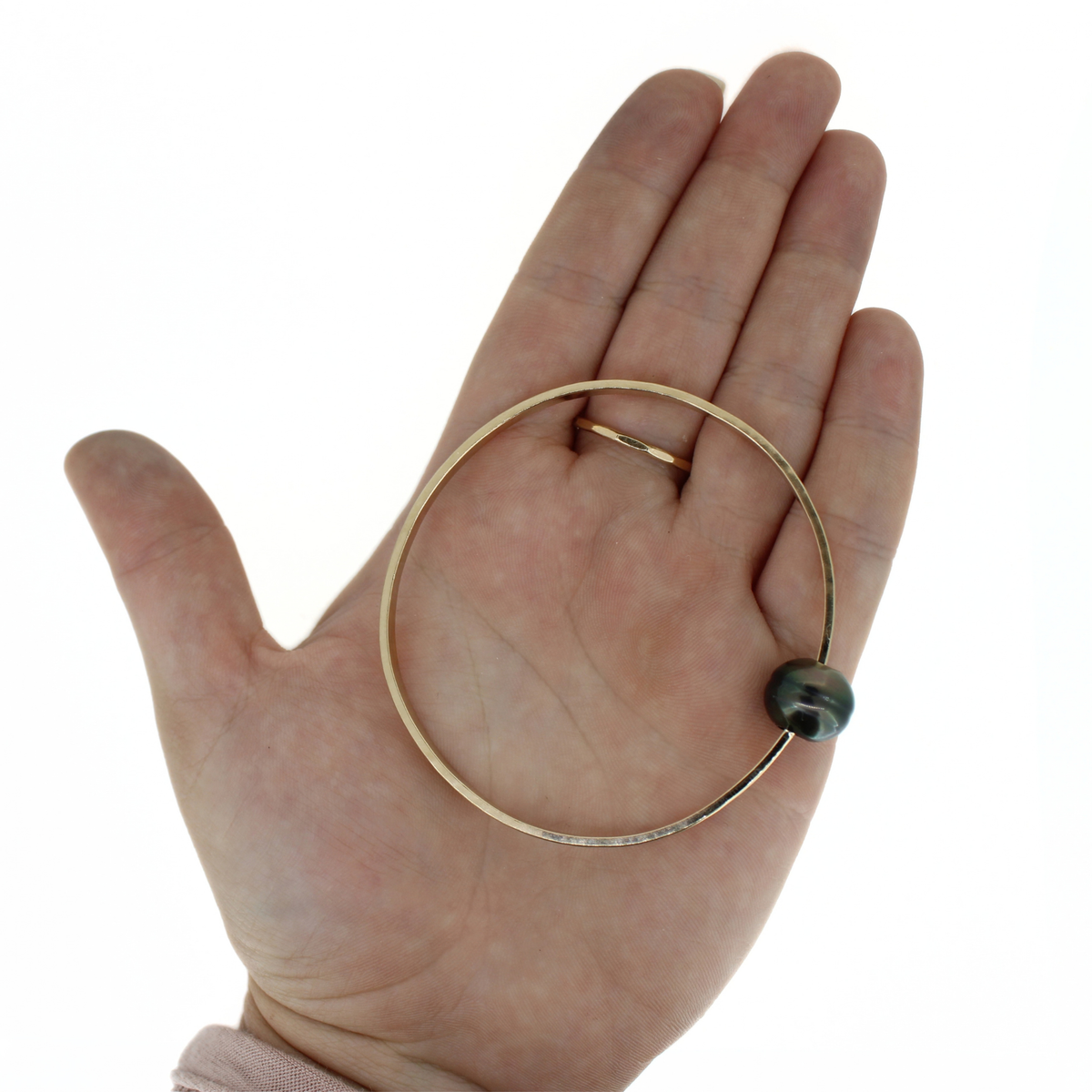 Gold Tahitian pearl bangle bracelet shown on an open palm for size reference