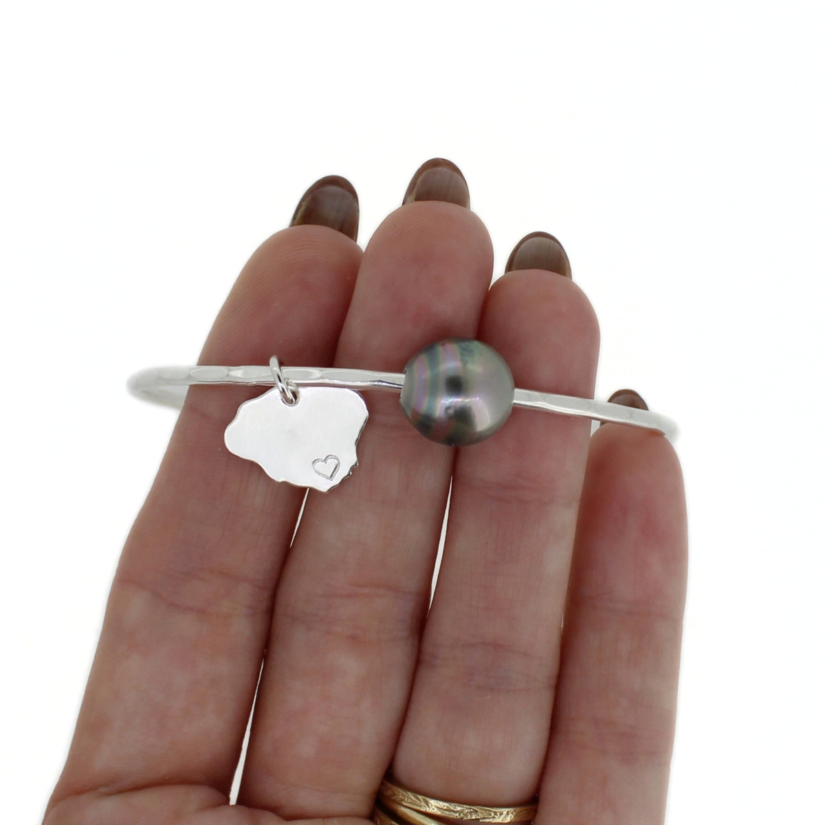 Silver Tahitian pearl bangle with Kauai island charm shown on a persons hand for size reference