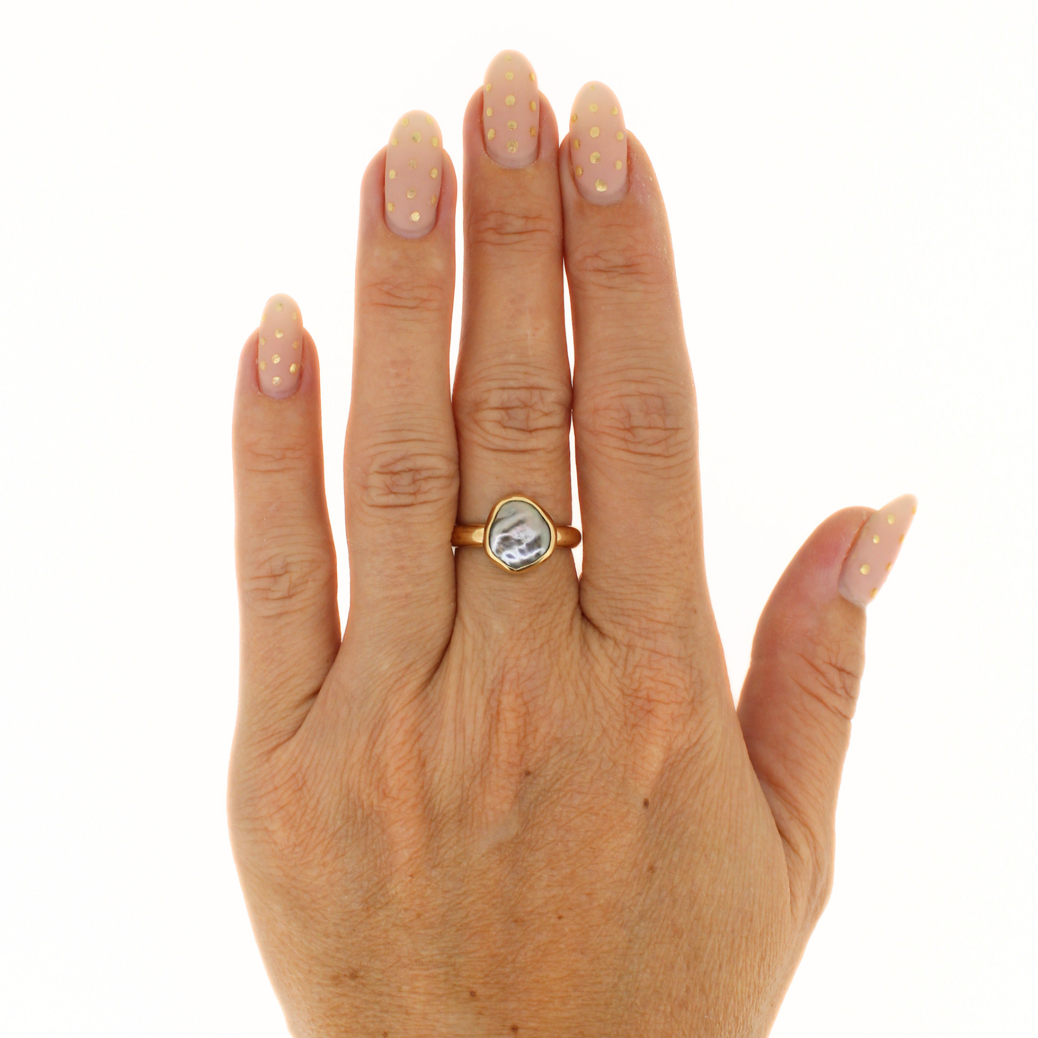 Gold-tone keshi pearl ring on hand, teardrop-shaped bezel with dark mottled pearl