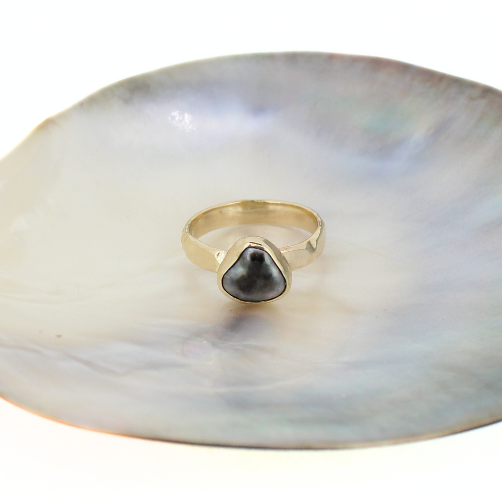 Gold ring with teardrop dark keshi pearl on iridescent shell dish