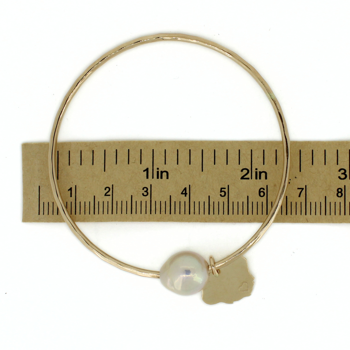 Gold pearl bangle over a ruler for size reference