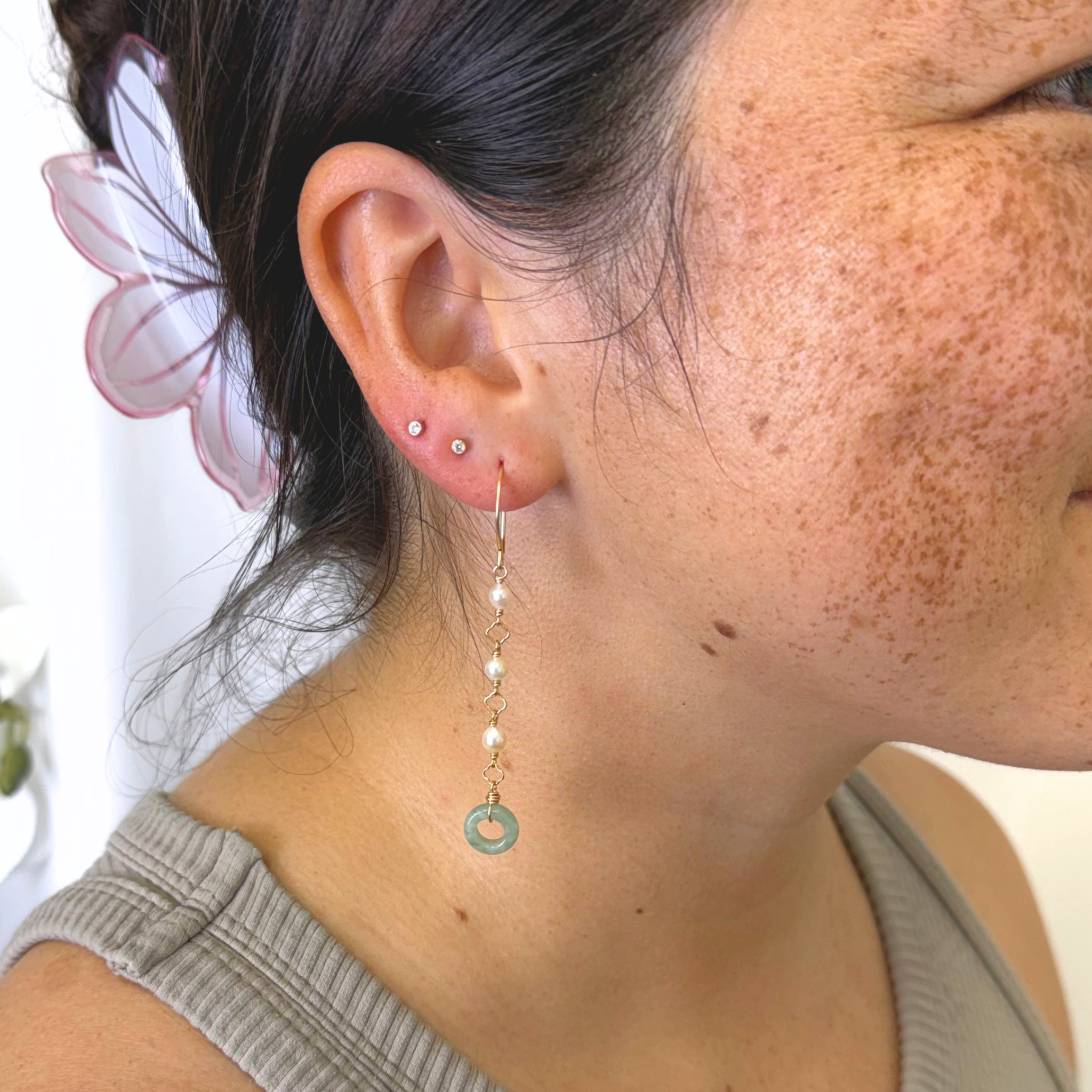 A close-up of a woman's ear wearing a long dangle earring.
