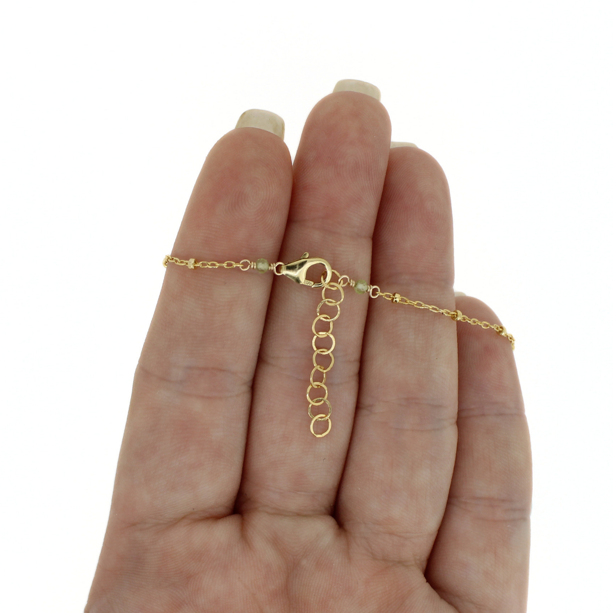 A delicate gold chain bracelet with a lobster clasp and extension chain, shown wrapped around a person's hand against a plain white background.
