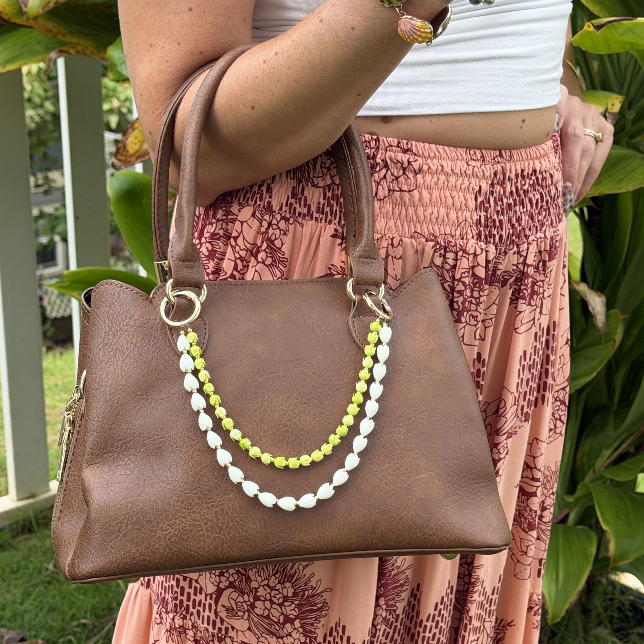 Brown tote purse with white and green double-strand flower lei necklace