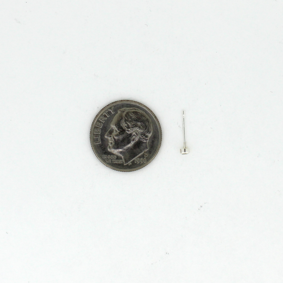 Tiny silver stud earring next to a dime for size reference
