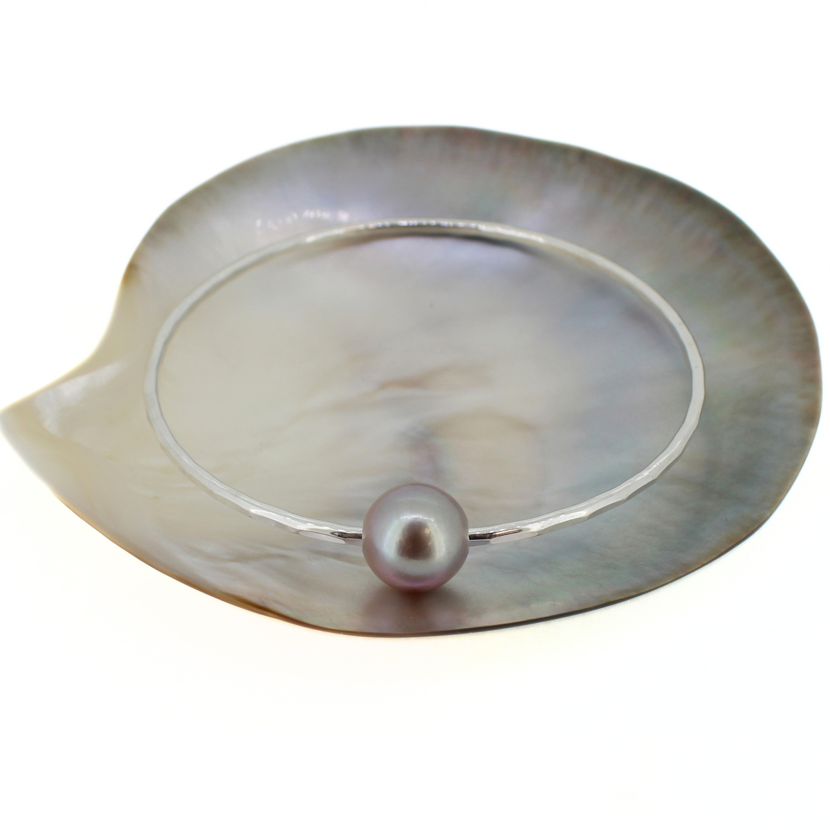 Sterling silver bangle bracelet with a light purple Edison pearl displayed on a mother of pearl shell