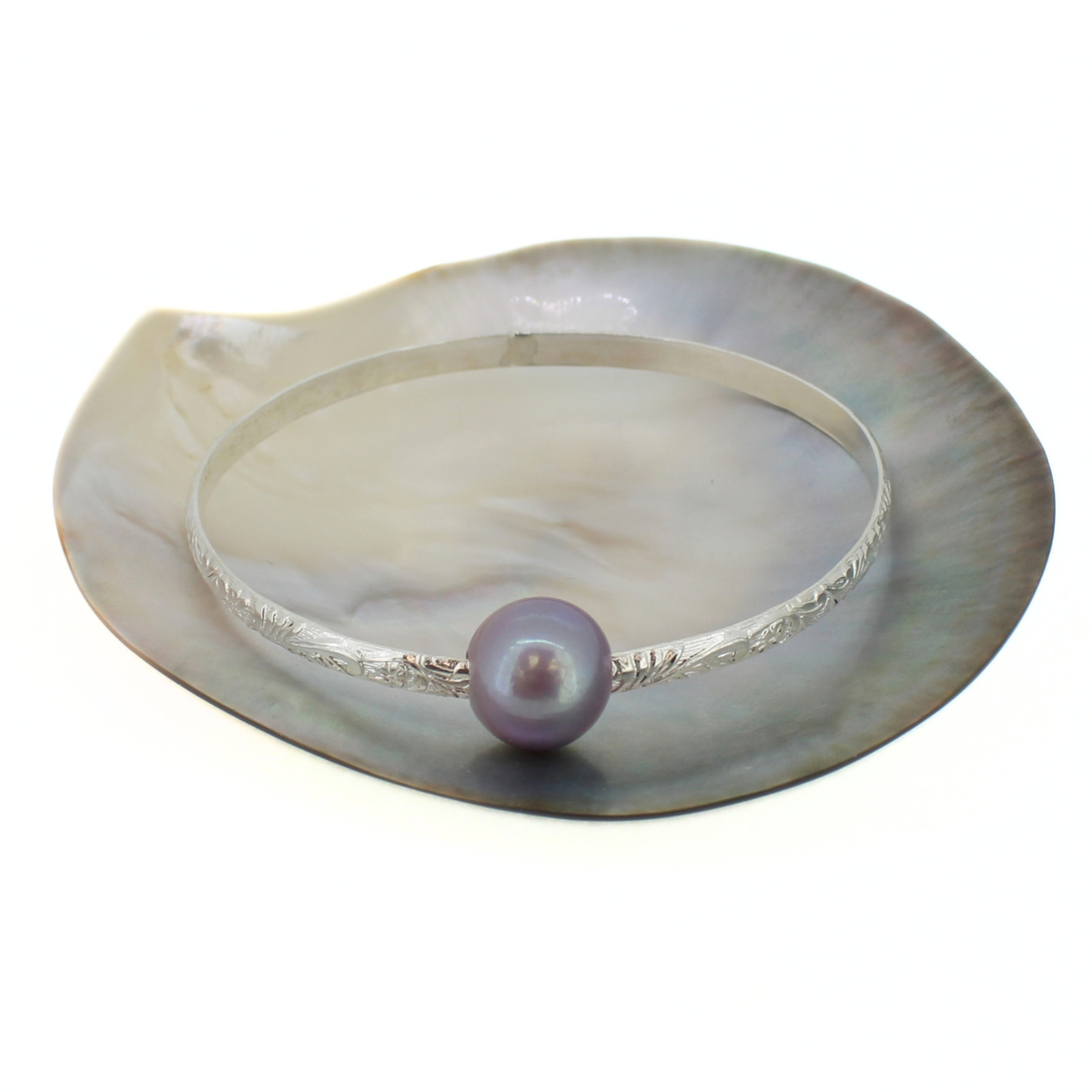 Sterling silver Edison pearl bangle with a floral printed design displayed on a shell against a white background