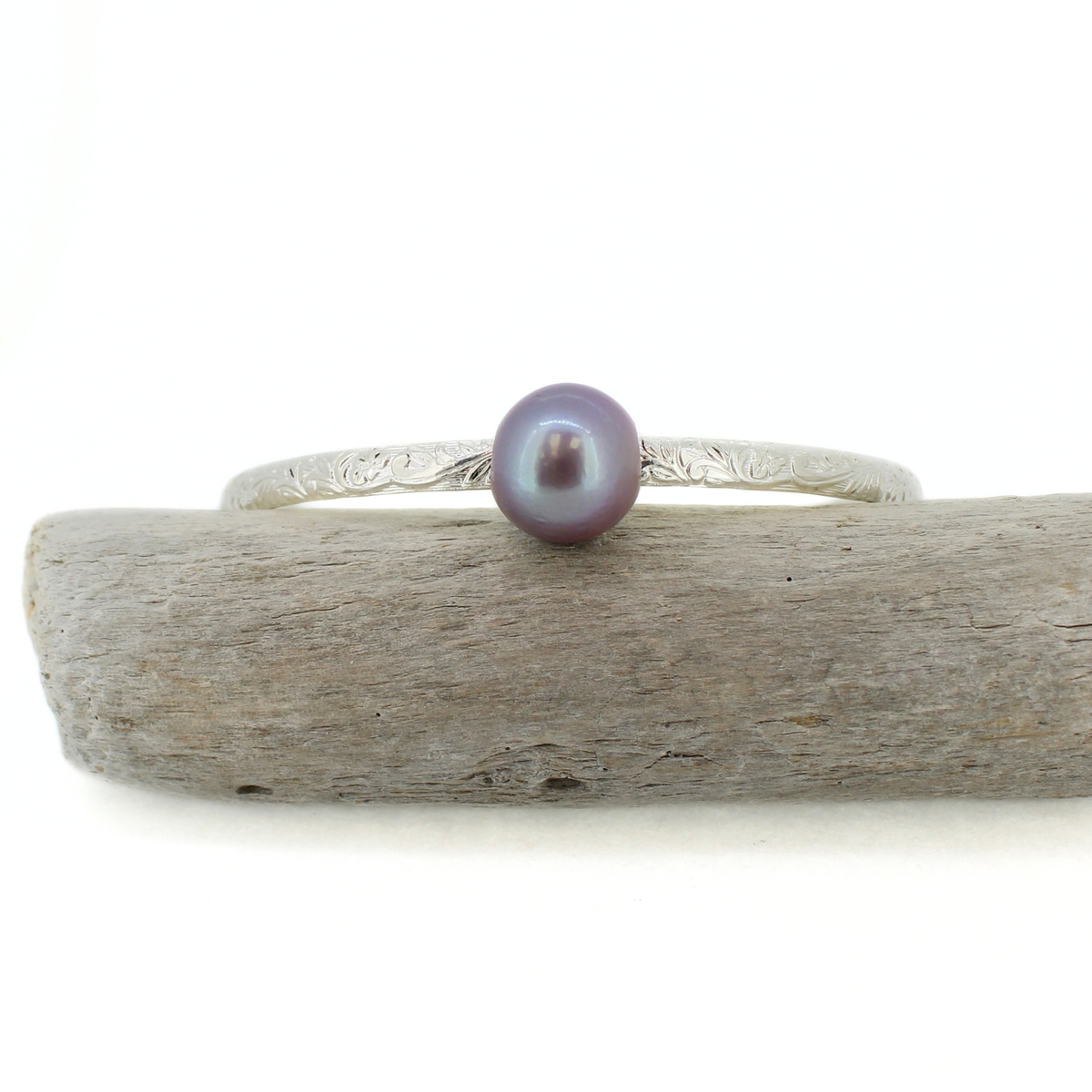 Sterling silver Edison pearl bangle bracelet displayed on a piece of driftwood