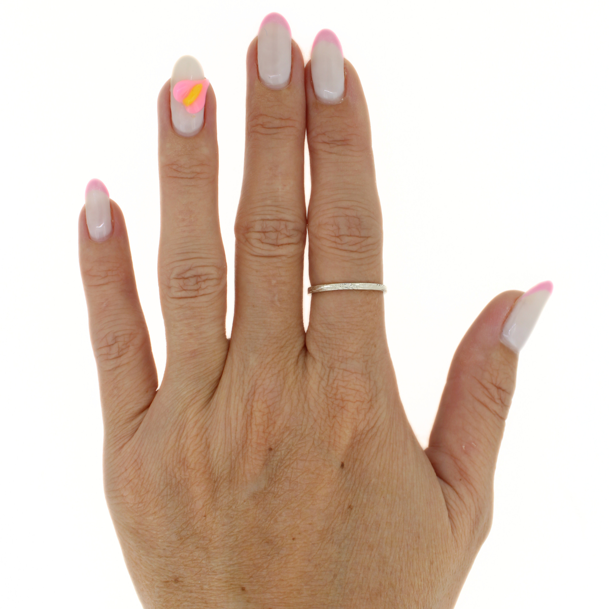 A close-up of a hand with long, glossy French-tip nails in white and pink, wearing a thin silver band ring on the ring finger against a plain white background.