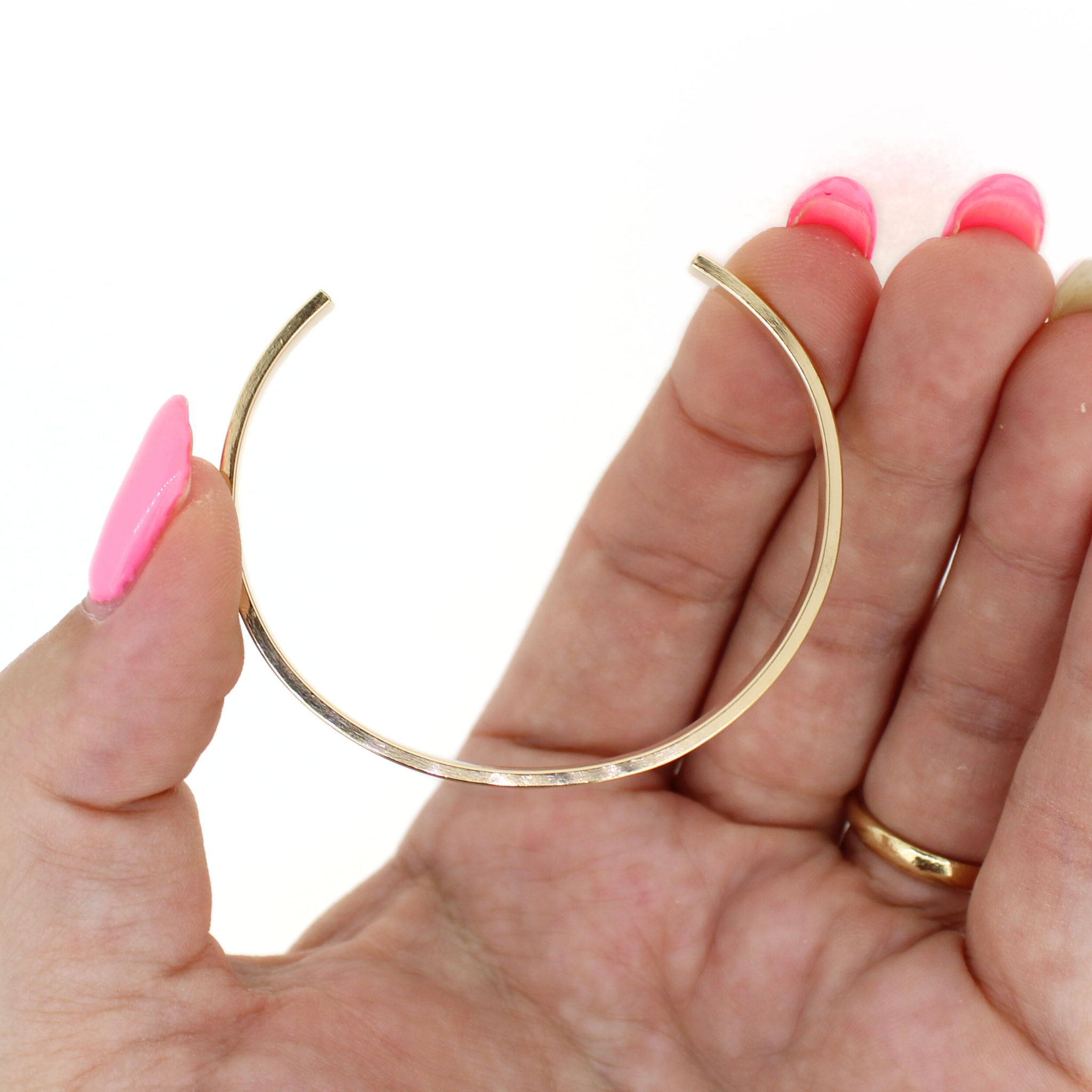 Gold fill cuff bracelet held in hand, smooth slim bangle with stamped ALOHA
