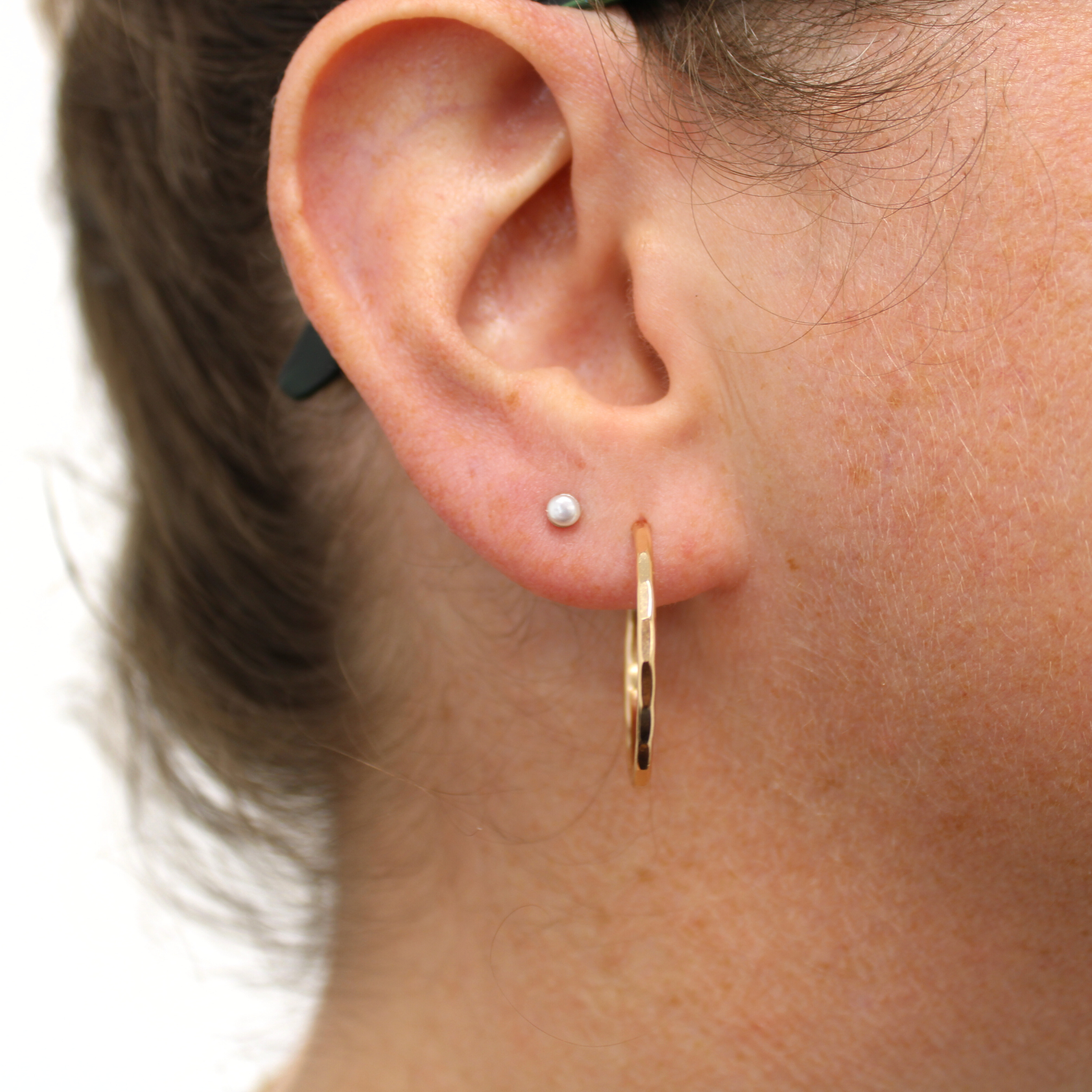 Sterling silver tiny freshwater pearl stud earring, close-up on ear
