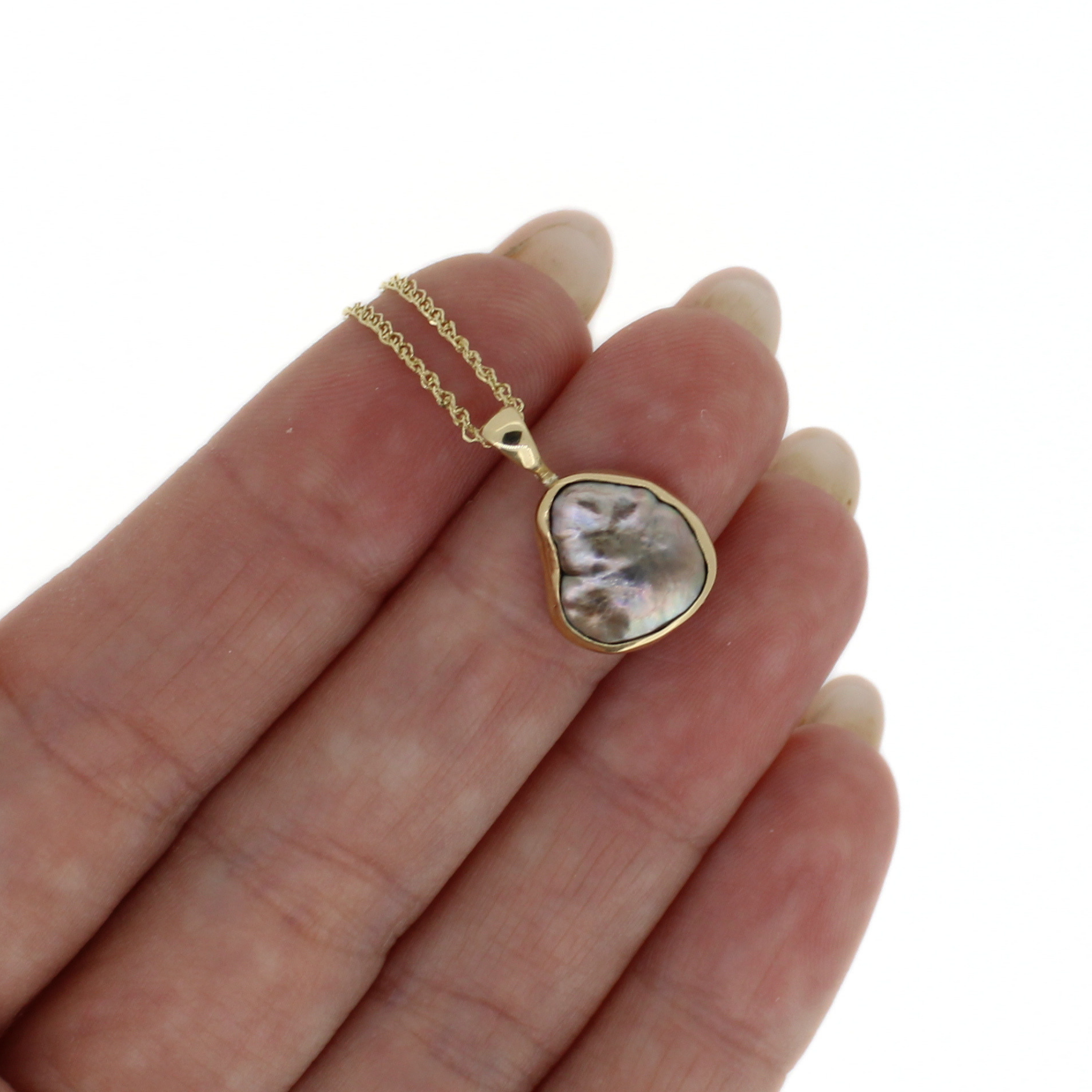 Gold keshi pearl pendant necklace, close-up of iridescent teardrop pearl on chain