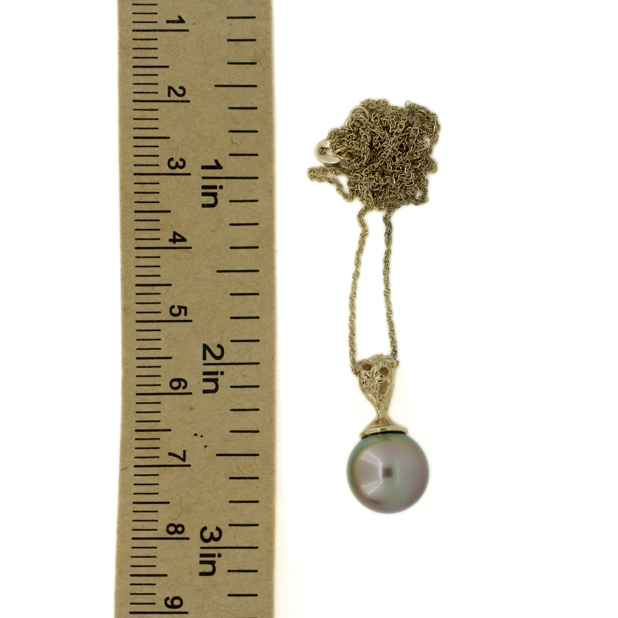 A 14k gold necklace with a round iridescent pearl pendant on a gold-toned chain, shown next to a ruler for scale on a white background.