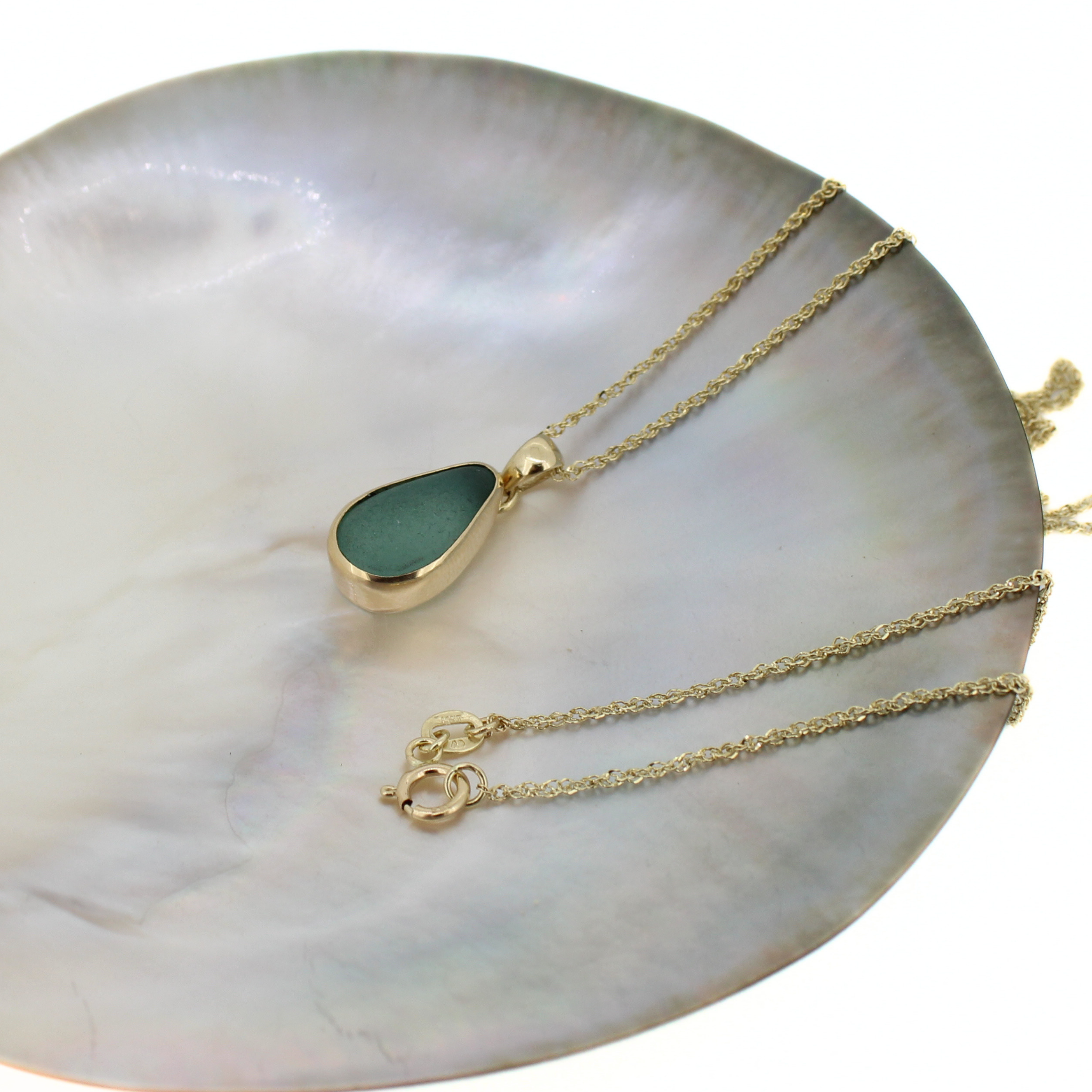 Gold sea glass pendant necklace with teardrop blue stone and clasp