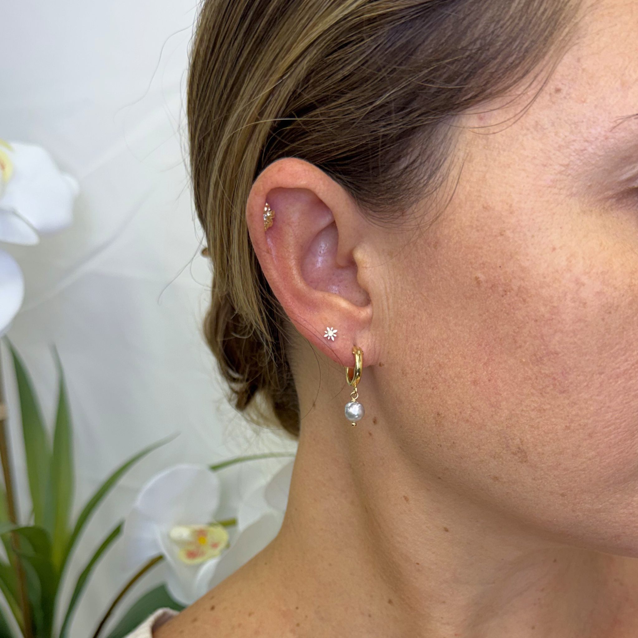 Gold hoop earrings with blue Akoya pearl drop and small star charm on ear