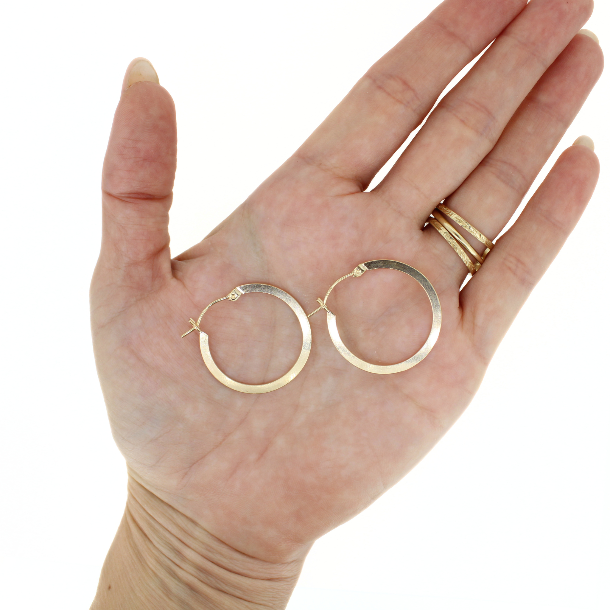 Gold-tone flat hoop earrings, 27mm, shown on open palm