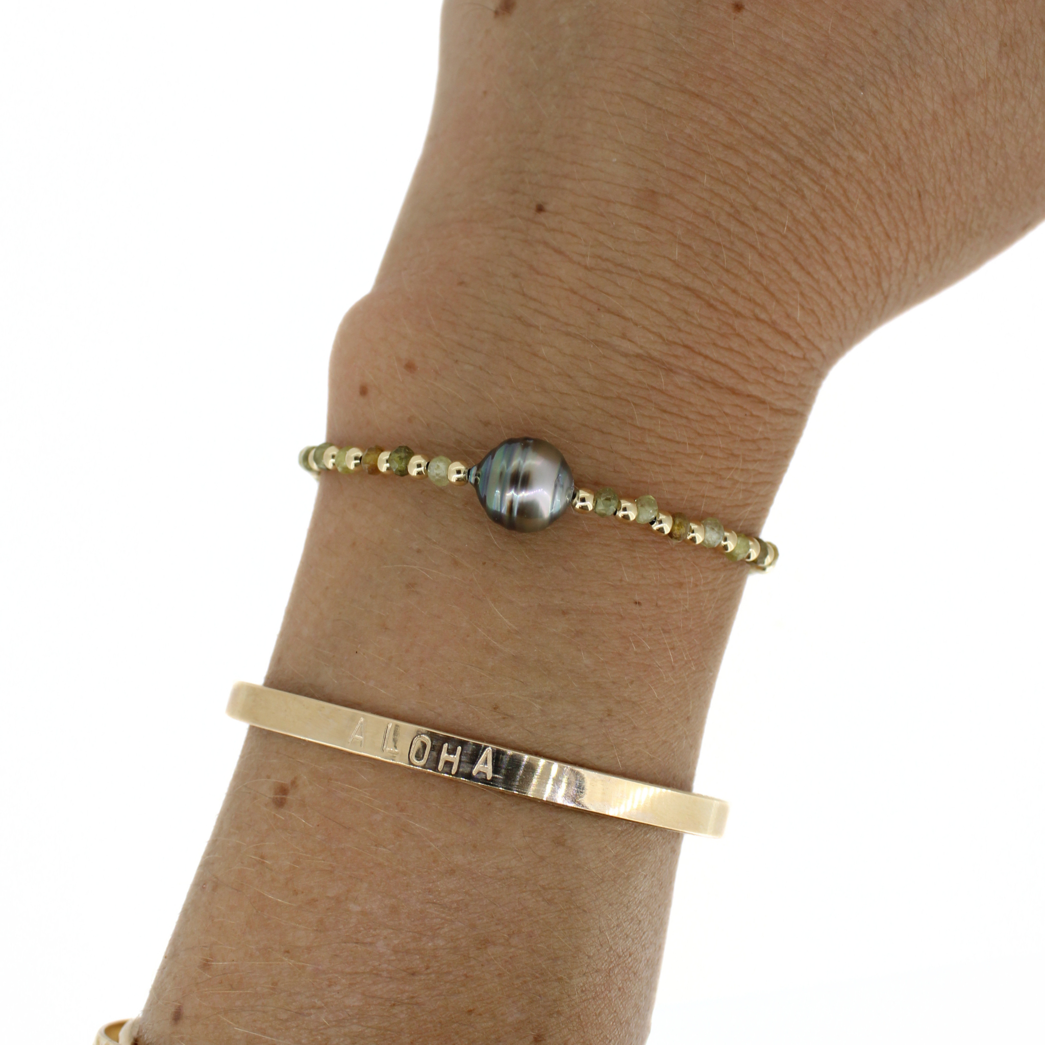 Bracelet with dark Tahitian-style pearl bead and gold beaded band on wrist