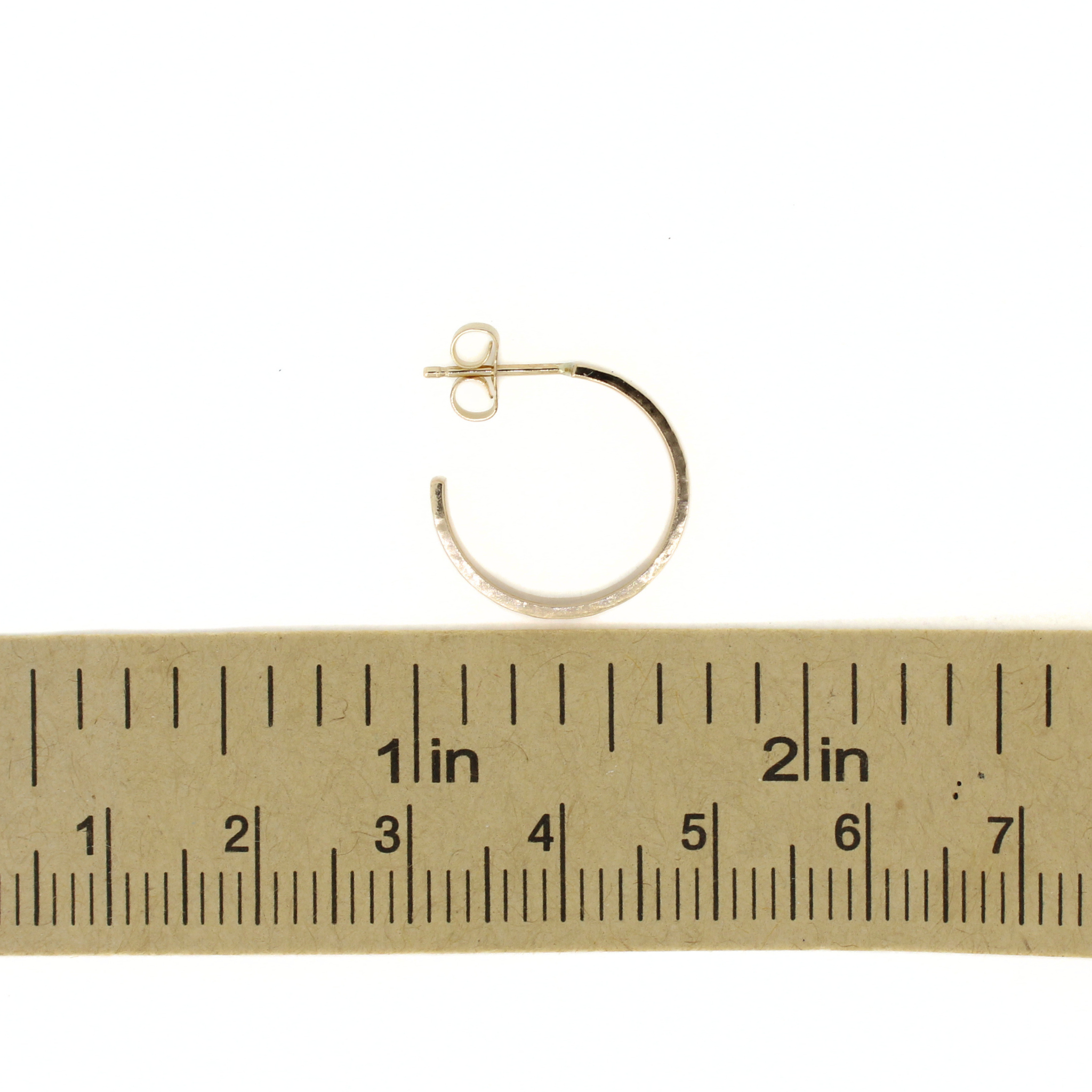 A small hoop earring in a yellow gold, shown above a ruler for scale on a white background.