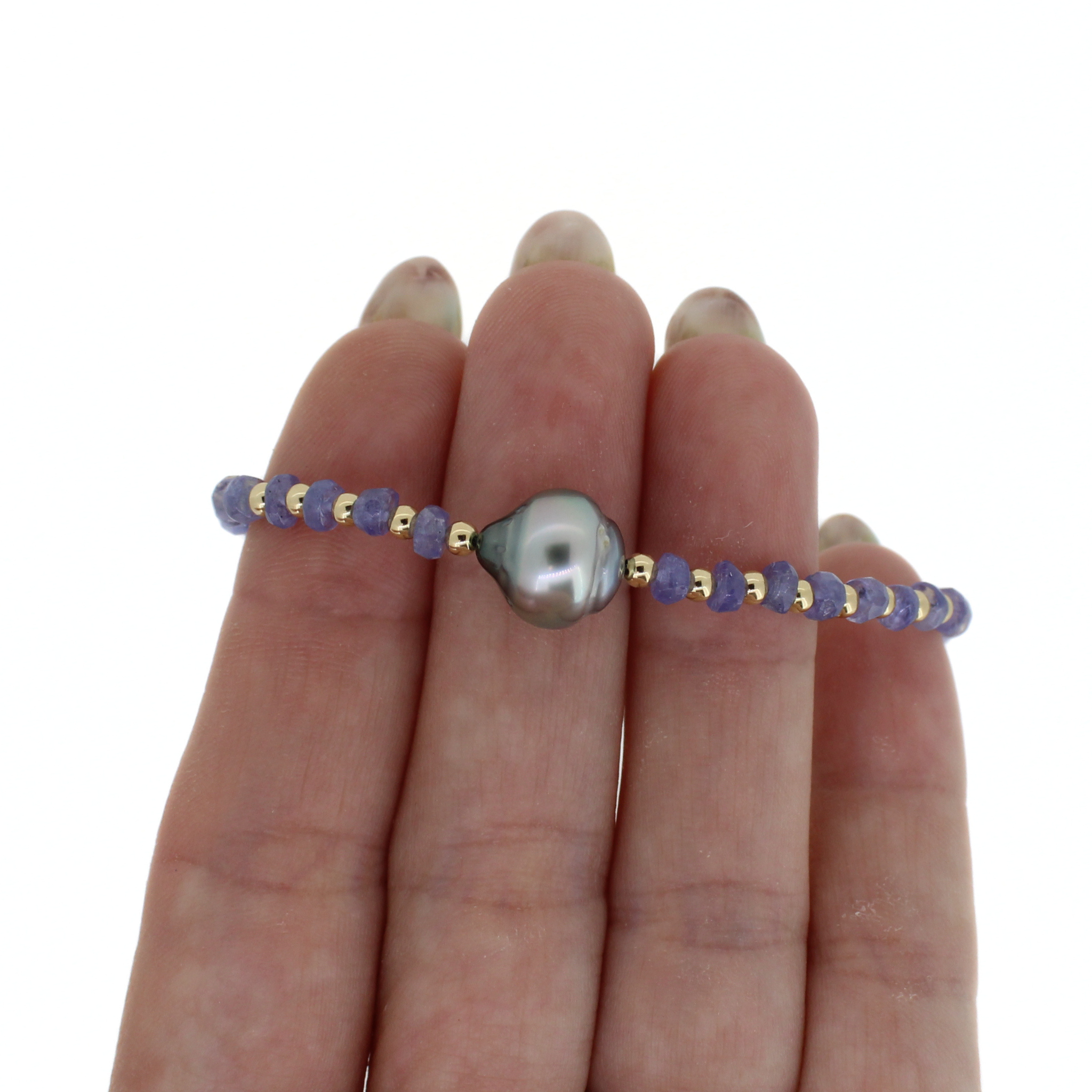 Bracelet on fingers: dark blue bead strand with large gray baroque pearl centerpiece.