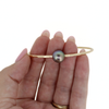 Gold bracelet with a pearl held in a hand on a white background