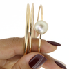 Gold bangle with a pearl on a white background