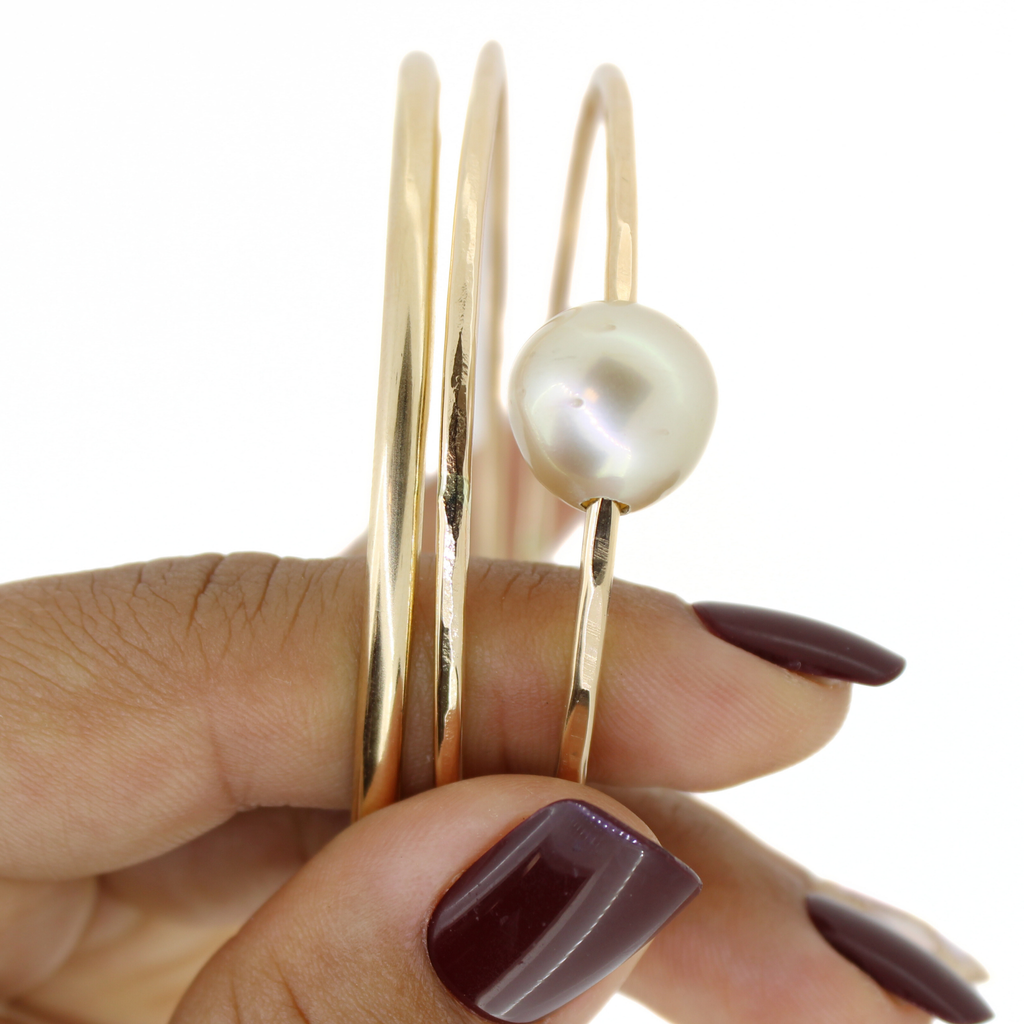 Gold bangle with a pearl on a white background