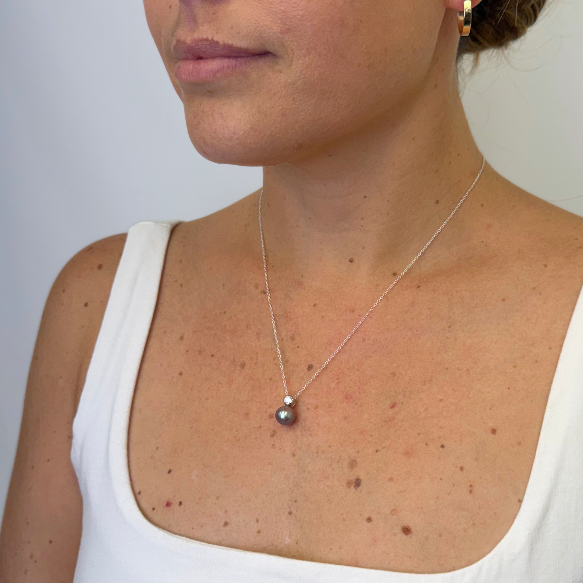 Sterling silver CZ purple Edison pearl necklace on a woman's neck, against a white background