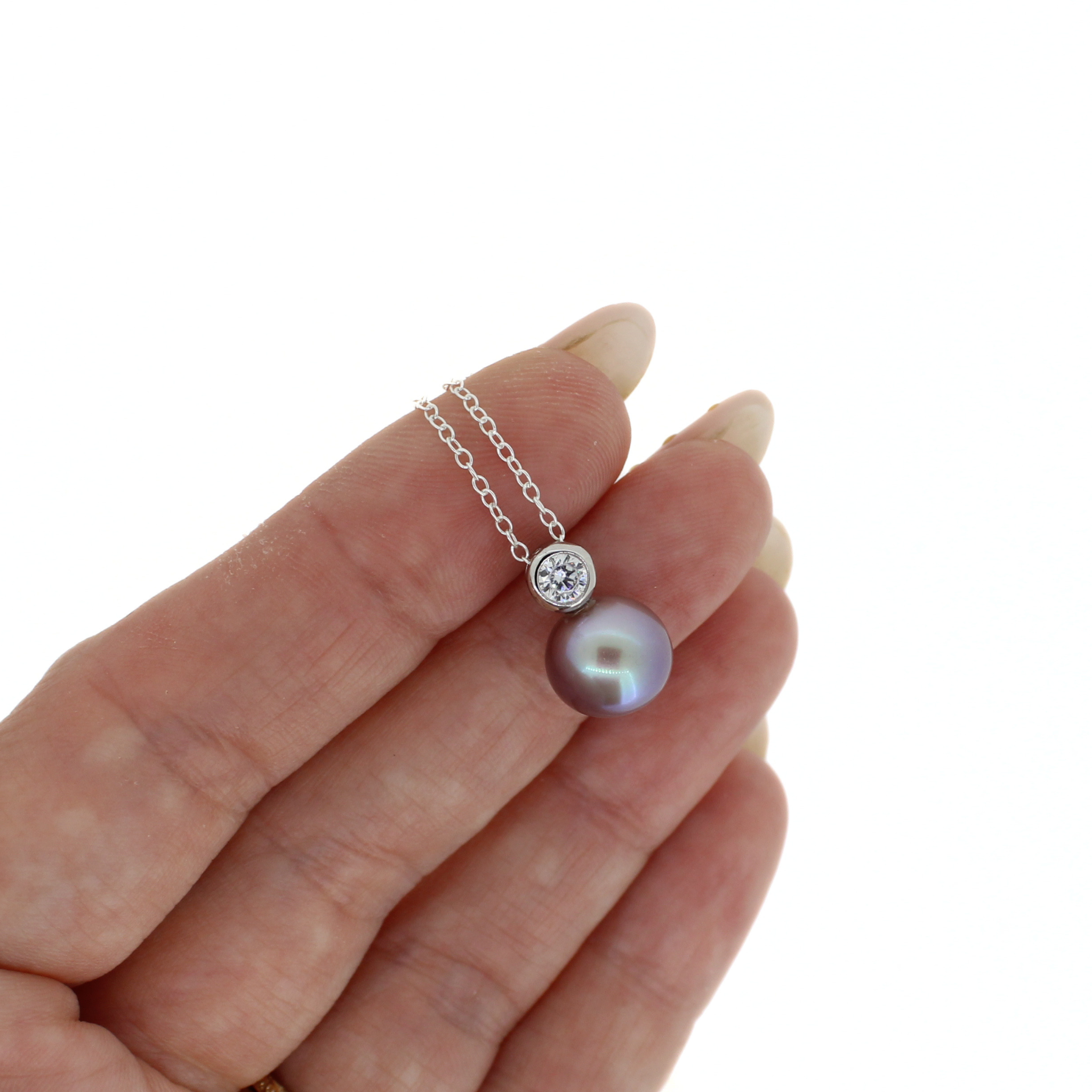 Sterling silver necklace featuring a bezel set clear cubic zirconia with a purple fresh water pearl.