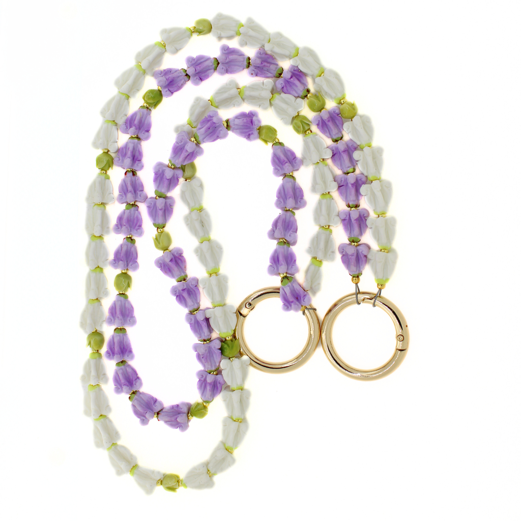 Brianne & Co. double strand purse lei featuring purple and white crown flowers and green pakalana flowers