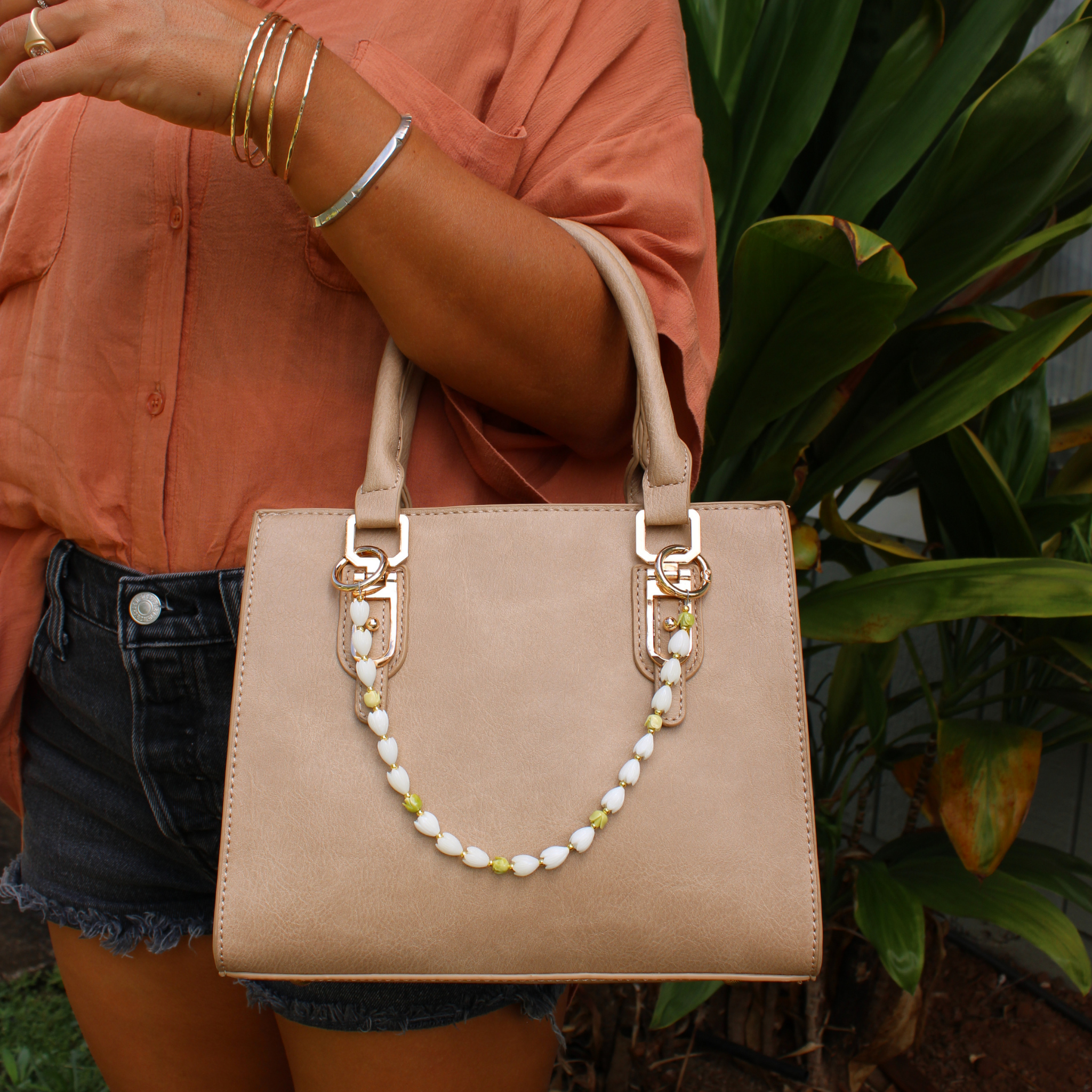 Beige handbag with short floral bead purse lei and hook clasp at each handle