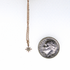 Brianne & Co. 14k rose gold diamond star necklace next to a US dime for size reference 