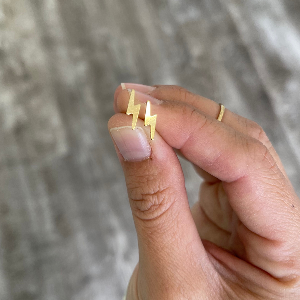 Brianne & Co. 14k gold filled small lightning bolt stud earrings in hand for size reference