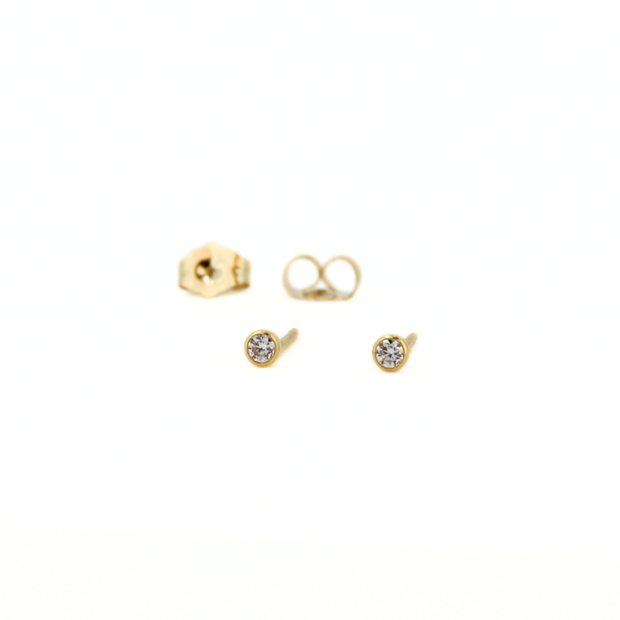 A pair of gold stud earrings with round clear gemstones, shown alongside their gold post backs on a plain white background.