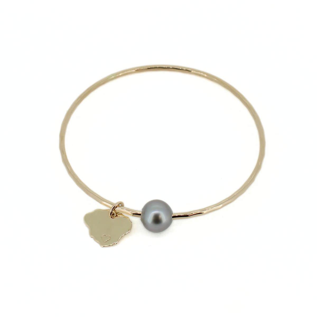 A delicate gold bangle bracelet featuring a small gray pearl and a gold Kauai-shaped charm, displayed on a clean white background.