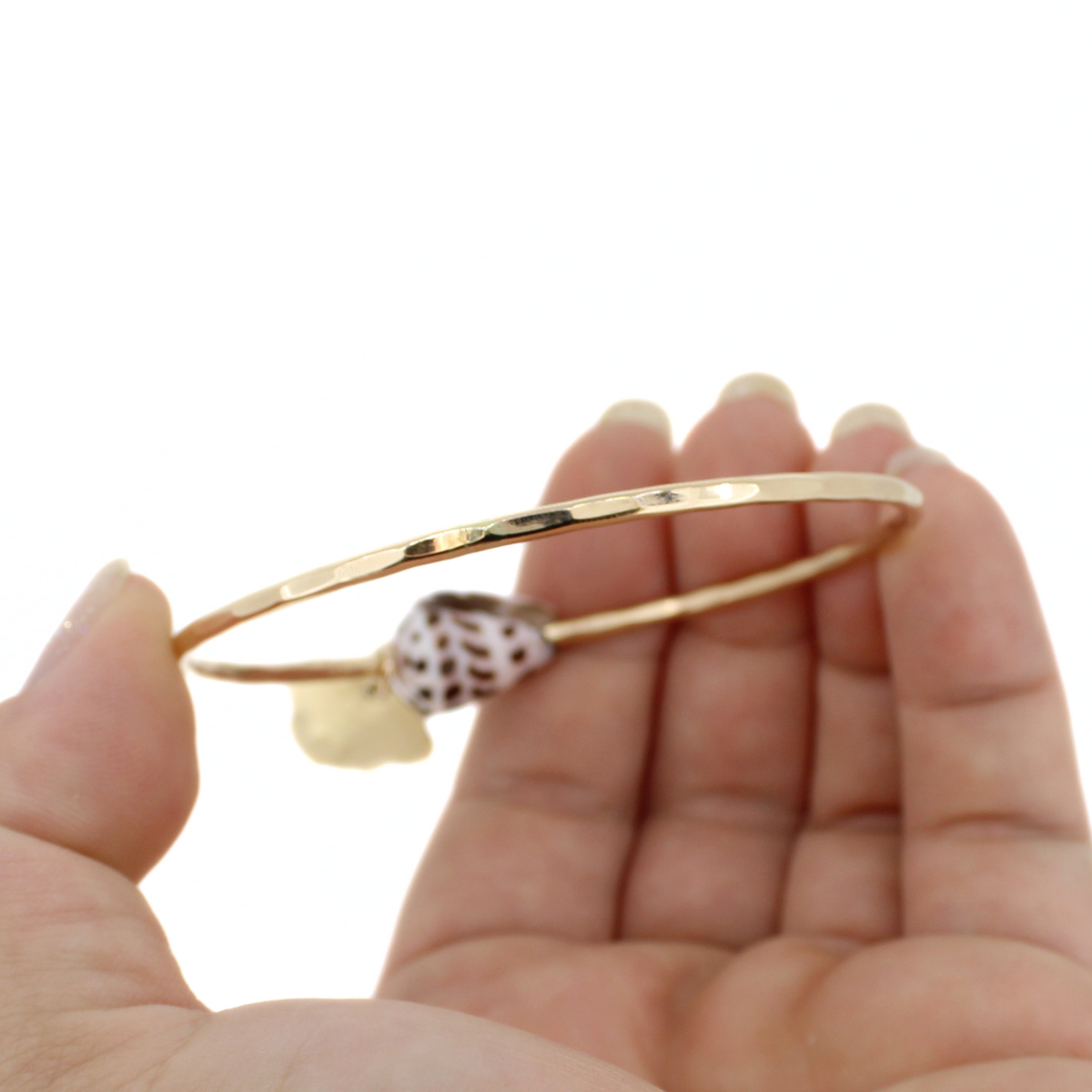 Gold bracelet showing the hammered texture against a white background