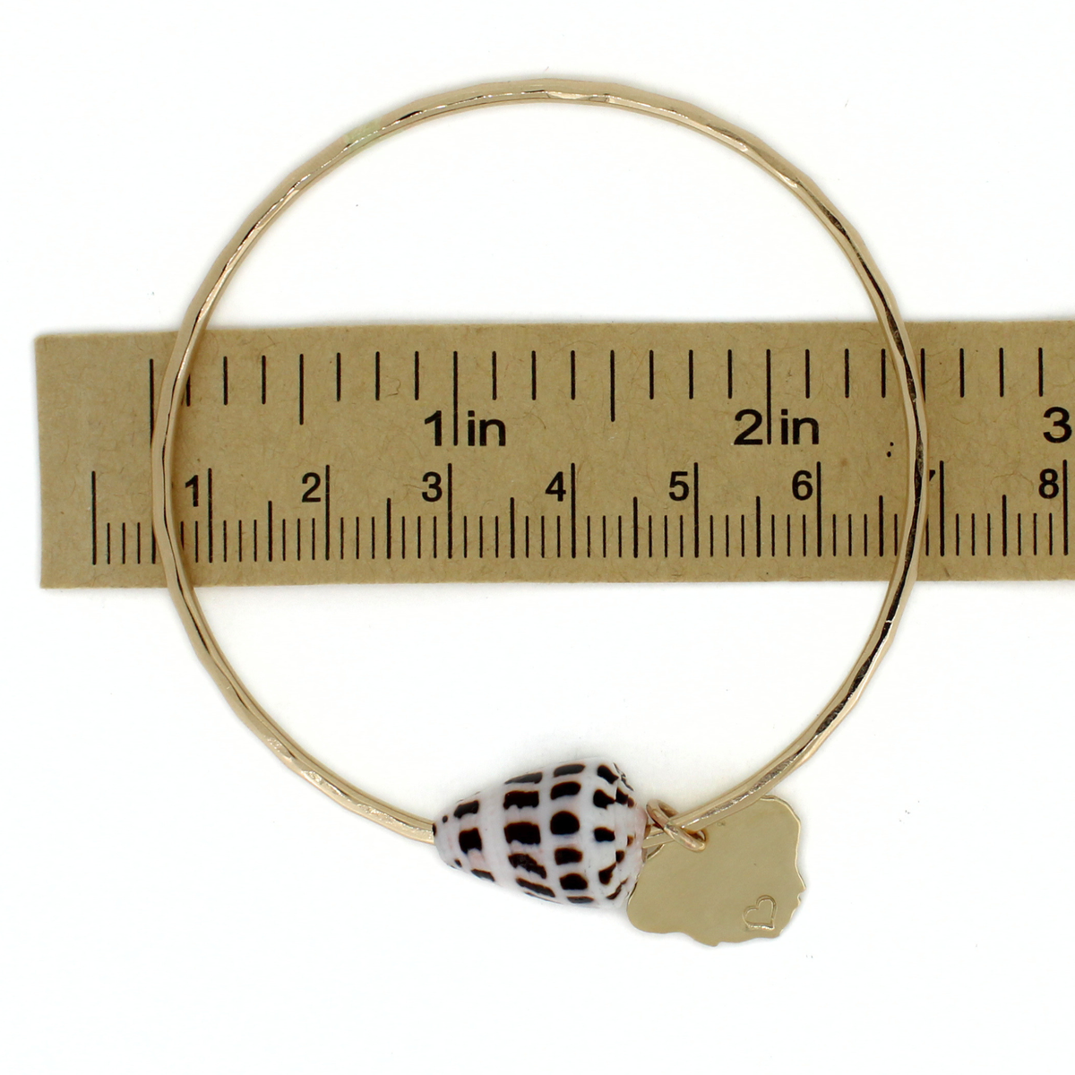 Gold cone shell and kauai charm bangle bracelet over a ruler for size reference
