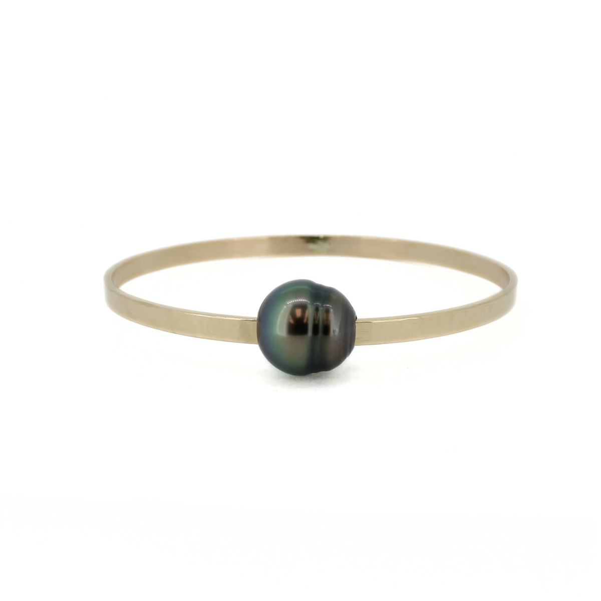 A minimalist gold bangle bracelet featuring a single dark, iridescent Tahitian pearl at the center, set against a plain white background.