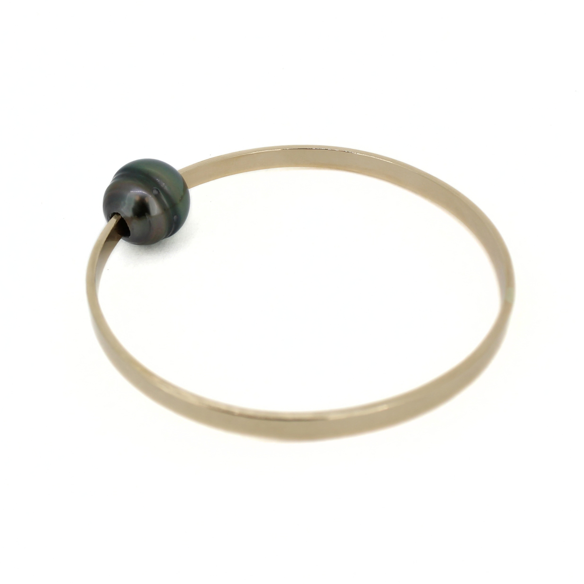 A thick gold bangle bracelet with a single dark, iridescent Tahitian pearl, shown on a plain white background.