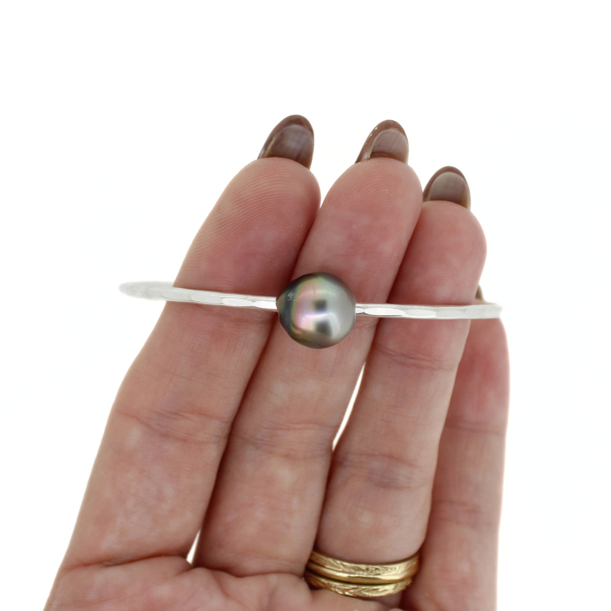Sterling silver Tahitian pearl bangle bracelet shown on a hand for size reference