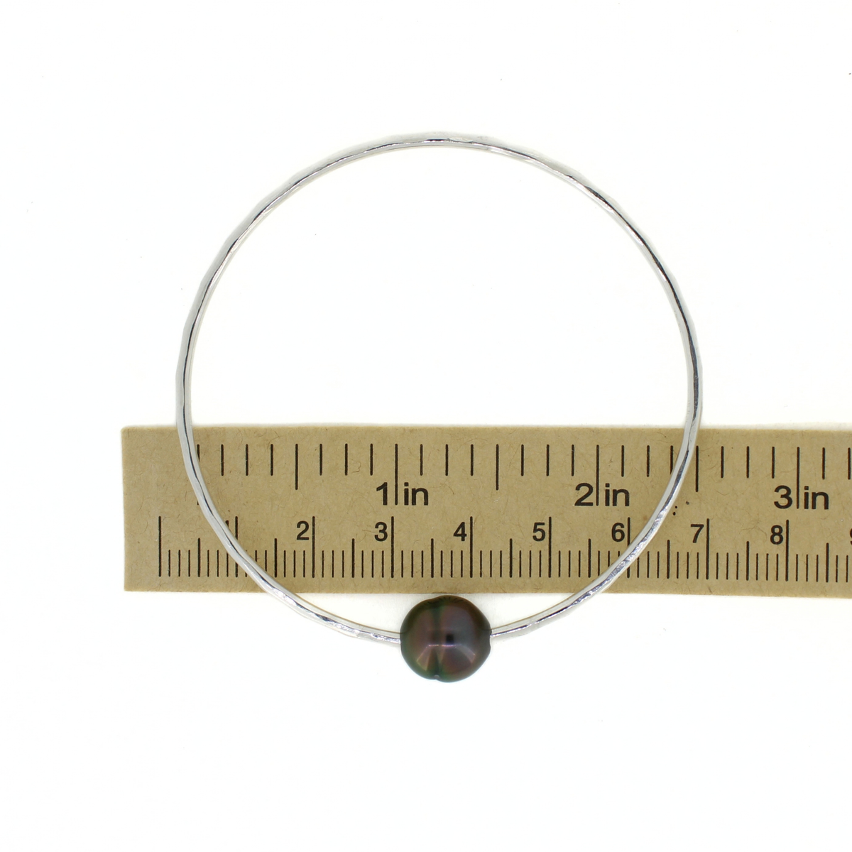 Silver Tahitian pearl bangle shown over a ruler for size reference 